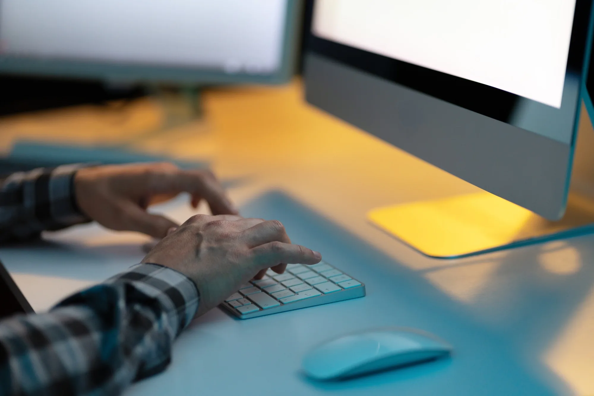 Man Typing on Keyboard in Dimly Lit Office Workspace